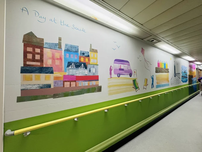 A long section of wall with a city scene and ice cream van in view
