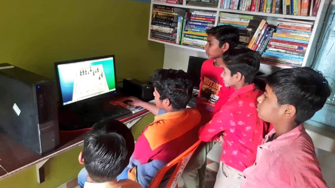 5 Junior group members playing chess on a computer in a free community library in Uttar Pradesh.