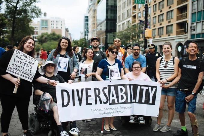Group of 11 people holding a Diversability banner at the 2018 NYC Disability Pride Parade