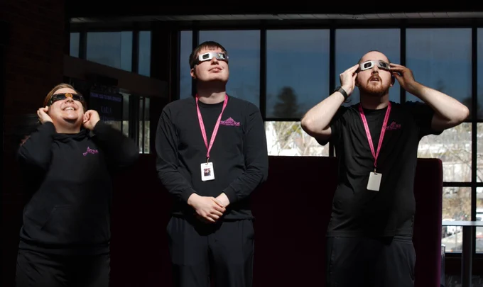 Prospects stand outside the Theater wearing solar eclipse glasses as they look to the sky.