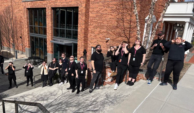 Prospects stand outside the Theater wearing solar eclipse glasses as they look to the sky.