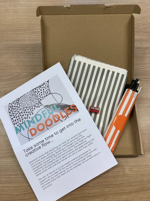 One of the activity packs called mindful doodles. It has a sheet of information and some colouring in pencils, pencil sharpener and cards inside a paper bag and all inside in cardboard box.
