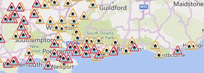 A map of the south coast shows a number of red and orange triangles that denote flooding is either expected or possible.