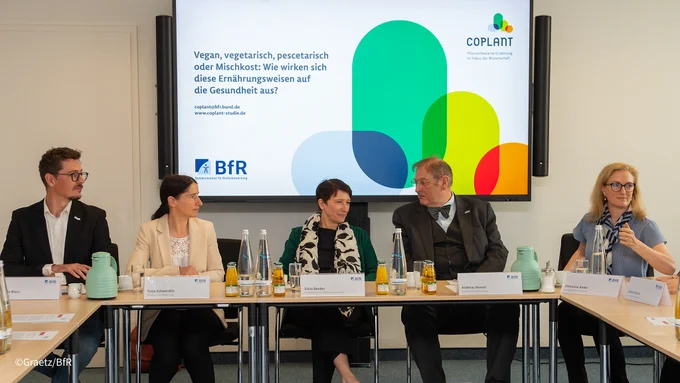 Staatssekretärin Silvia Bender, Präsident des BfR Prof. Andreas Hensel, Vizepräsidentin Professor Prof. Tanja Schwerdtle und zwei weitere Personen sitzen an Tischen. Im Hintergrund eine Präsentation.