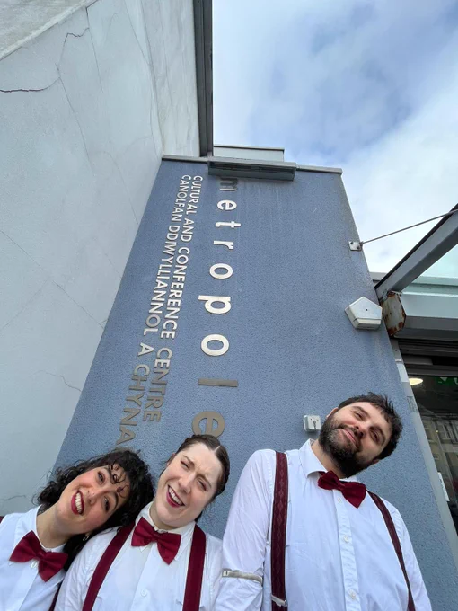 3 performers tilting their heads in front of the Met in Abertilery