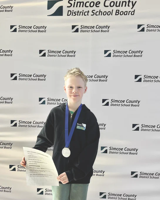 Student smiling into camera with medal