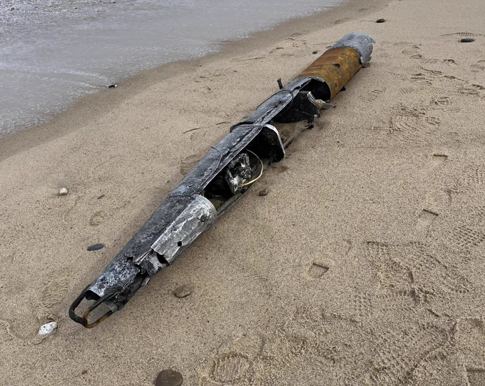 The remains of a remote control aerial target fuselage laying in the sand.