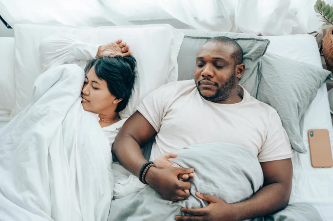 A woman and a man are asleep in bed.