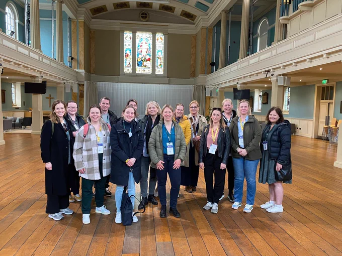 A group of people standing and smiling in a church hall.