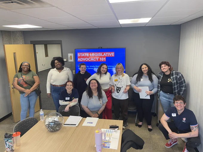 Group photograph of ACLU-WI staff and UWM students smiling in front of a computer screen reading "State Legislative Advocacy 101"