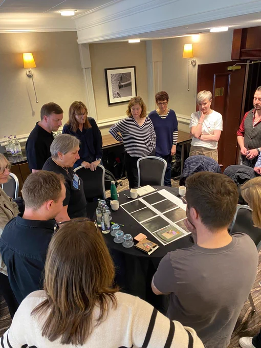 Group of people stood around a table looking down at a group activity 