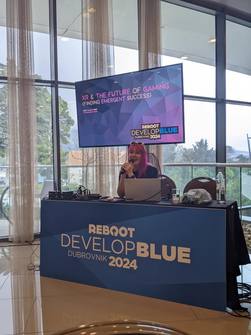 Ashley sitting at a desk, in front of a screen titled "XR and the future of gaming" 