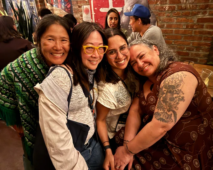 At the BGDM/A-Doc meetup, four women of color from BGDM huddle together happily for a photo. 

