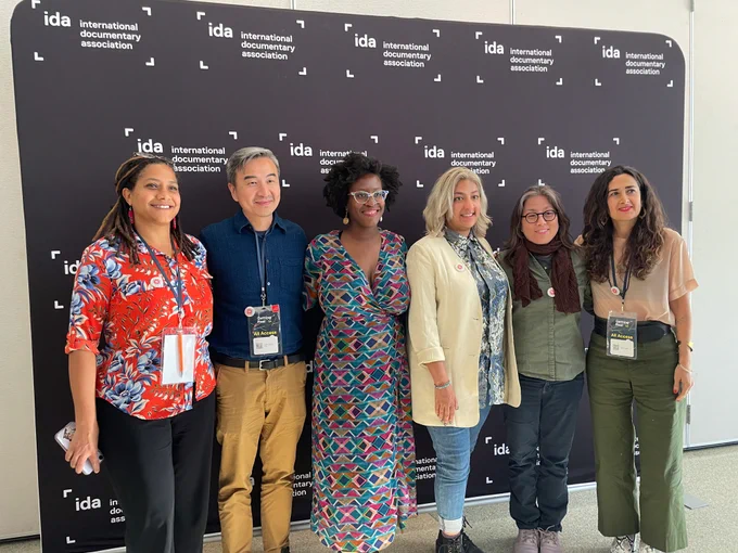 In front of an IDA Getting Real step-and-repeat backdrop, BGDM, A-Doc and Color Congress leaders smile. From left to right, Black Sonya Childress from Color Congress, Asian Leo Chiang from A-Doc, Black Iyabo Boyd from BGDM, Bangladeshi Farihah Zaman from BGDM, Asian Grace Lee from A-Doc, and Iranian Sahar Driver from Color Congress.
