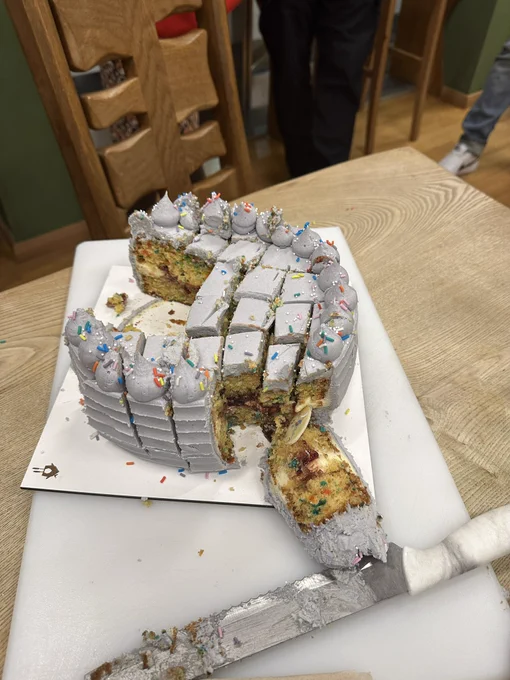 Image shows a half demolished cake with silver frosting and rainbow sprinkles