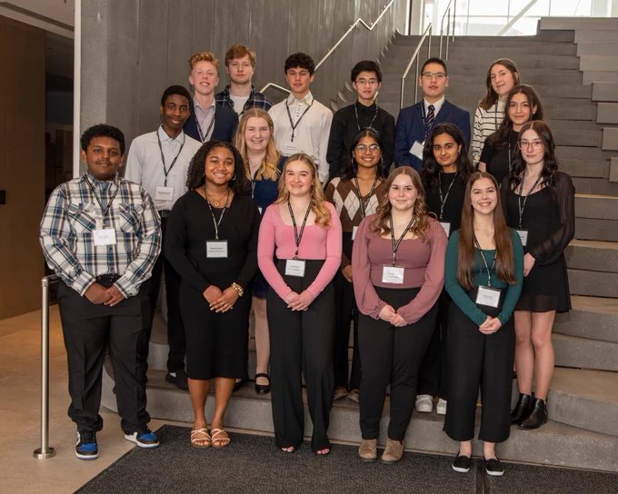 A group of 17 students pose on a stairway. 