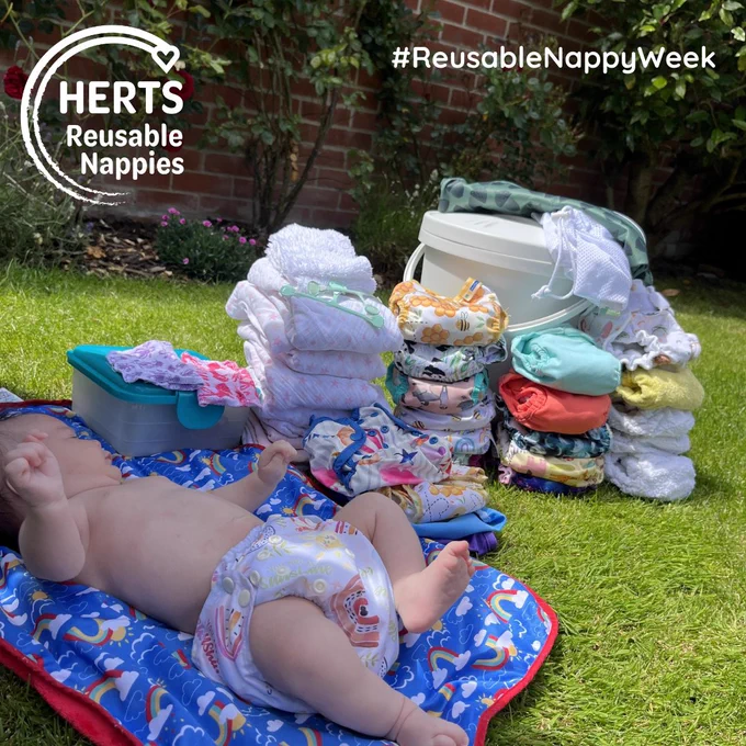 Baby lying on changing mat surrounded by reusable nappies
