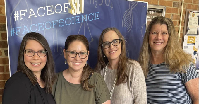 Four St. Mary's University women faculty members from the department of Biological Sciences in front of a blue #faceofscience background.