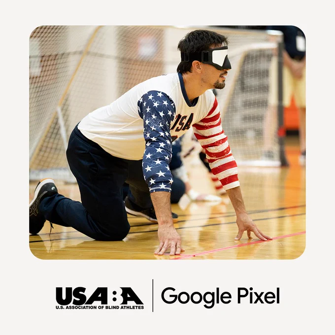 A person crouching with an eye covering over their eyes. USA is written on their shirt.