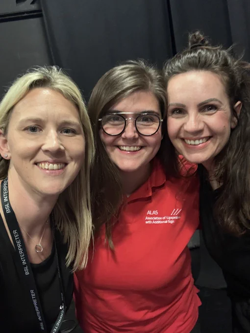 Three women posing for a picture. All women are visibly smiling.