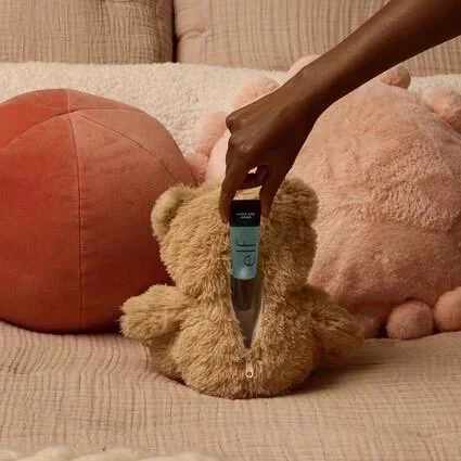 Teddy bear with a zipper down its back opened to show a tube of E.L.F. makeup