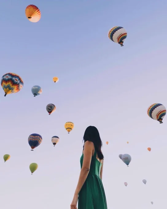 woman looking upwards to the hot air balloons shot on iPhone