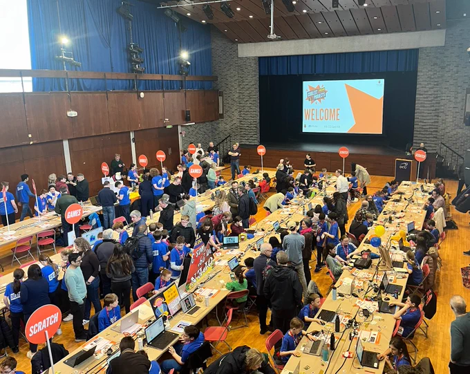 A overhead shot of the Coolest projects venue showcasing all of the young creators, mentors, judges and projects on long tables.