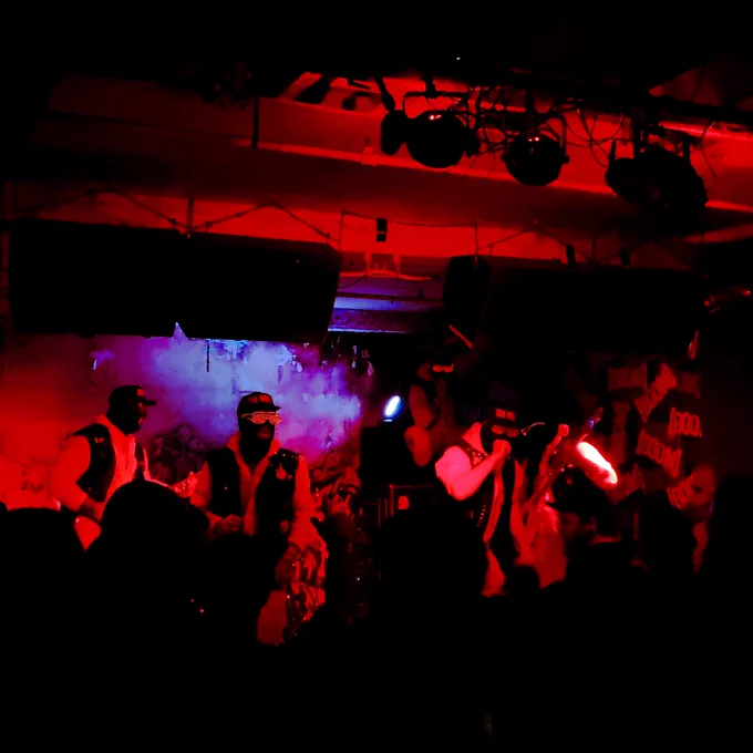 The Hell playing at BOOM, Leeds. The band are all wearing matching outfits with black ski masks, red light up glasses and caps with the band name on.