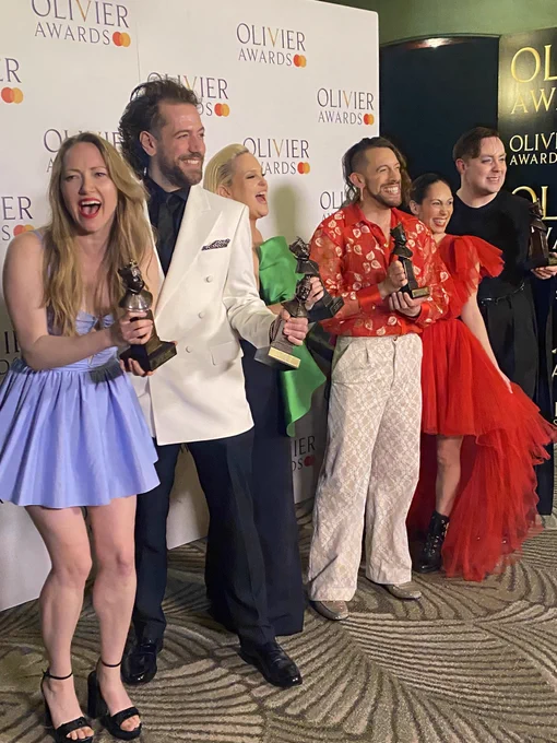 A photo showing a group of performers standing and smiling together
