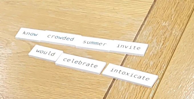 Word tiles arranged on a tabletop to spell out "know crowded summer invite / would celebrate intoxicate"