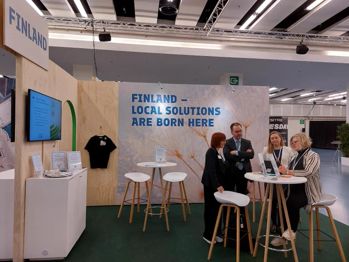 People are sitting in at the expo. On the wall you can read Finland - Local solutions are born here.