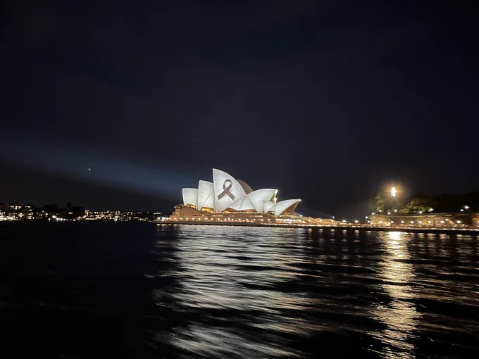 Sydney Opera House lit up with a black ribbon on the sails.
