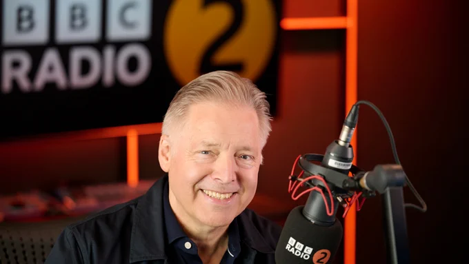 Mark Goodier sits behind a Radio 2 microphone in a BBC Radio 2 studio