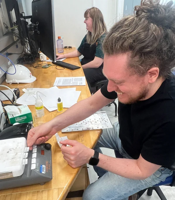 Luca Magri (Sedimentologist, IMAS, University of Tasmania, Australia), front, works on smear slides with Lorna Kearns (Sedimentologist, UTIG, USA). (Credit: Tomoaki Morishita & IODP) 