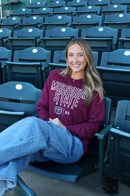 Student sitting in baseball stadium in maroon long sleeve shirt 