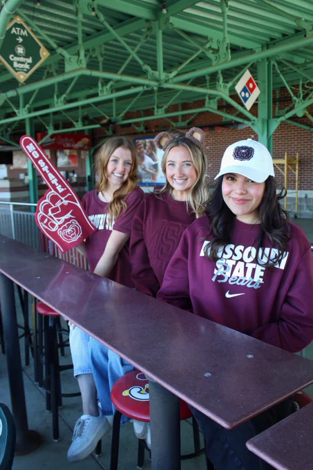3 students posing at bar top table wearing their Bear Wear 