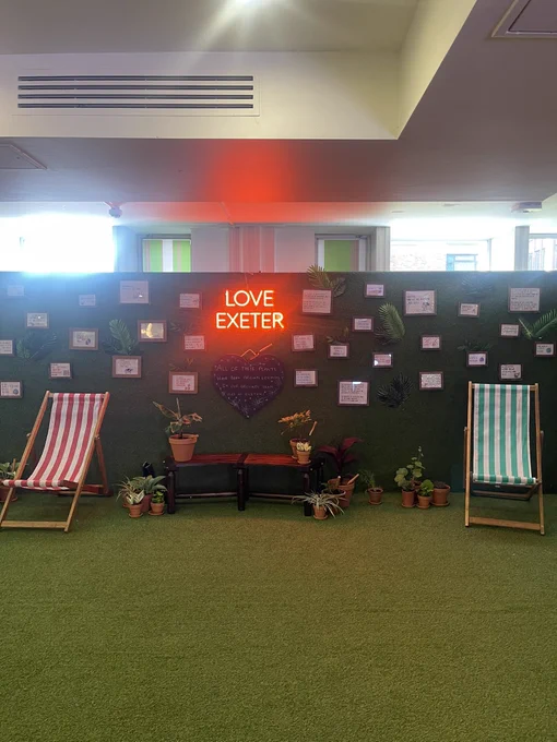 Inside garden with fake grass, beach chairs and Love Exeter LED sign.