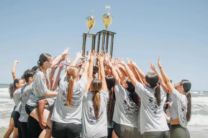 Cheer and dance team members holding their huge trophies in the air