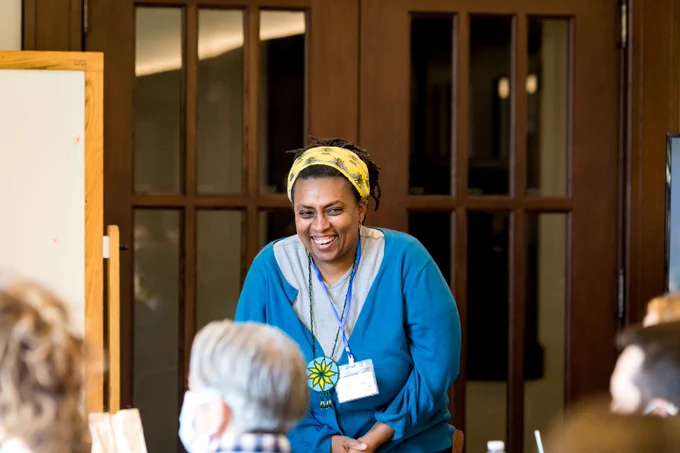 Michelle King leans forward with a smile in front of a group of educators.