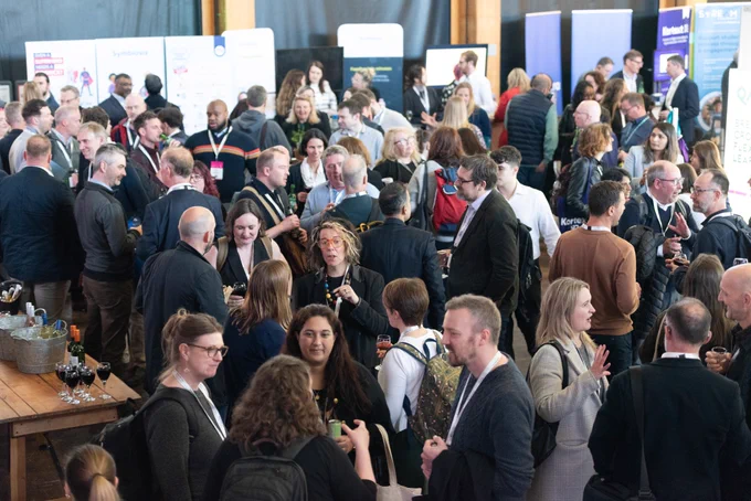 Room full of people networking at an event.
