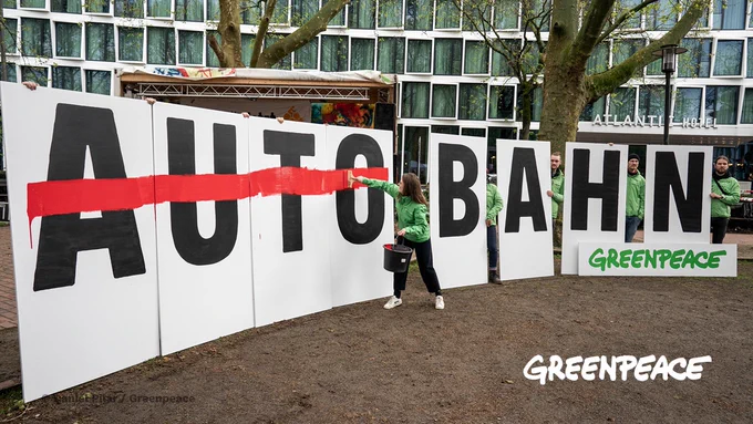 Riesige Buchstaben die das Wort AUTOBAHN ergeben sind aufgereiht, eine Person streicht das Wort AUTO durch