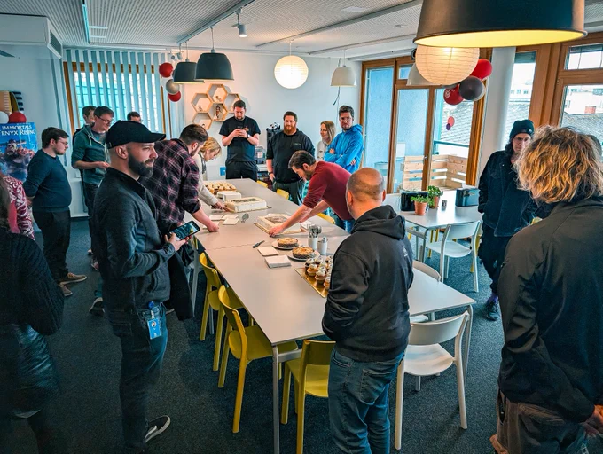 Our team members gathered around a table while one is cutting the cake.