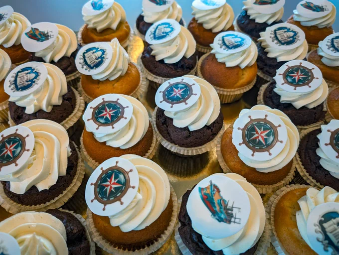 A bunch of cupcakes with Anno 1800 art on it. 