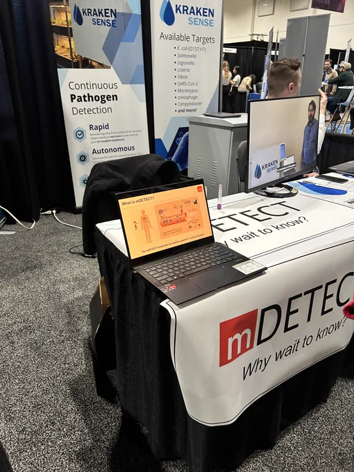 mDETECT booth with company logo, backdrops and screen for visual demonstrations.