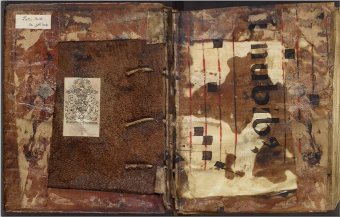 Latin MS 104, waste in binding. Stained and overlaid covering, with large stitches and book plates.