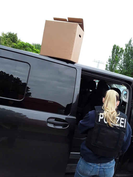 Polizistin mit Umzugskarton am Dienstfahrzeug