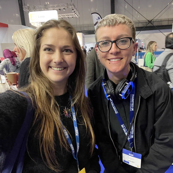 A photo of two people smiling in a crowded exhibition hall.