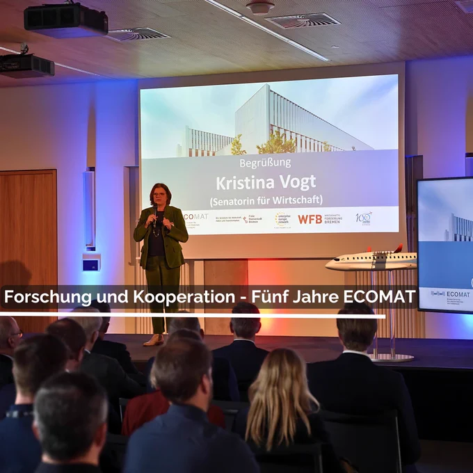 Senatorin oft hält ein Grußwort. Text im Bild: Forschung und Kooperation - Fünf Jahre ECOMAT