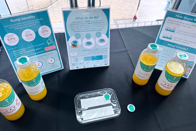 Close up of the Mimica booth at Barclays Corporate Connections Sustainability Showcase. Bump Caps on juice bottles are displayed, along with a Bump Tag sample and informational posters about the science behind Bump technology.