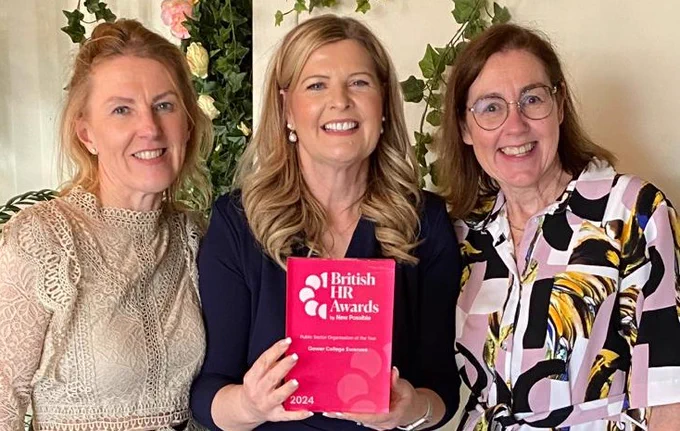 Three women, smiling and holding award